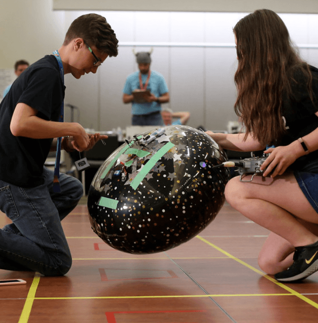 Two students steering a starry balloon through a course